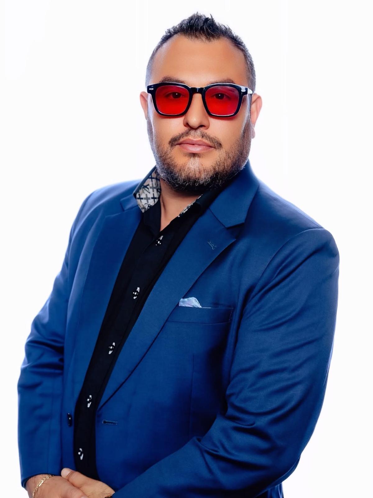Antonio Hondo Parente wearing a blue suit and red glasses